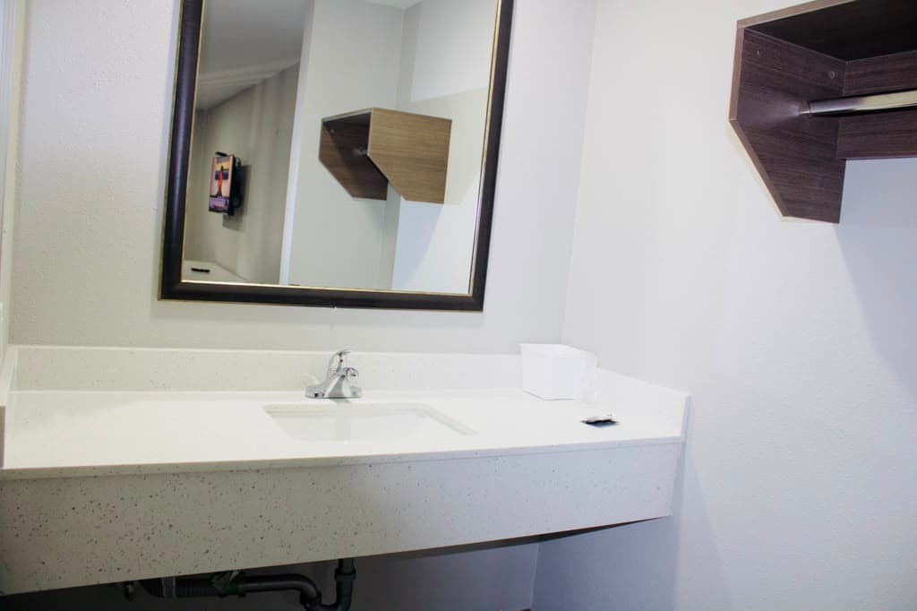 Vanity with large framed mirror and open closet shelf