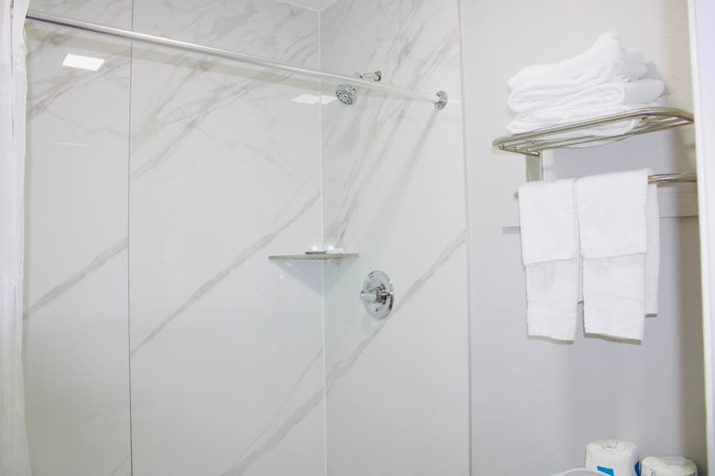 Marble-look walk-in shower with fresh towels on the rack