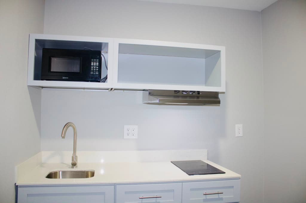 Kitchenette counter with sink, induction cooktop, and microwave