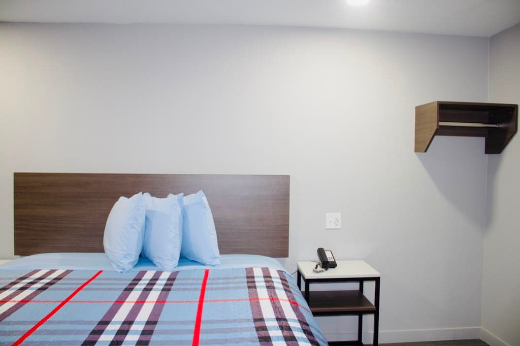 Bed with soft blue pillows, phone, and open closet shelving