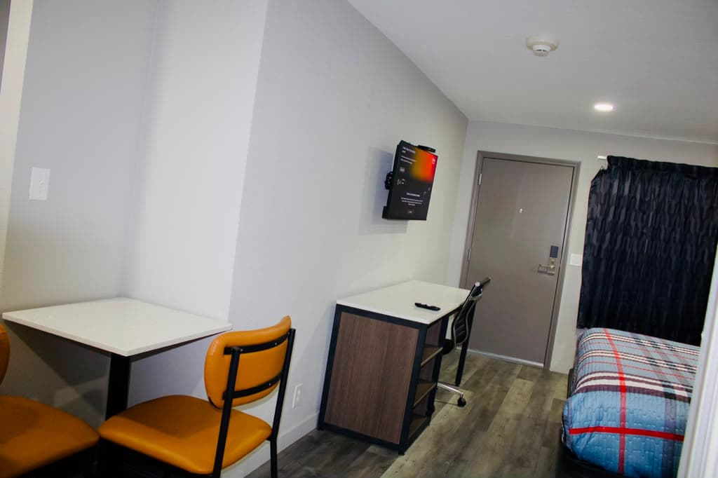 In-room dining table and chairs by the entry with wall-mounted TV