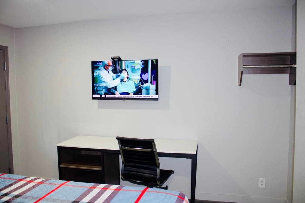 Wall-mounted TV above the work desk and office chair