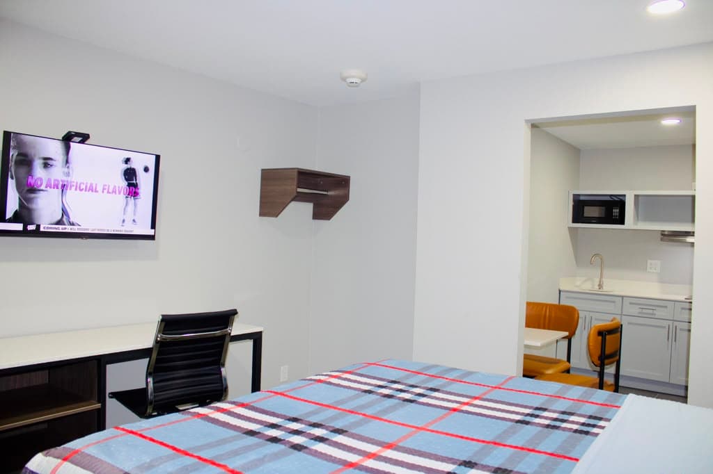 Studio suite with TV, desk, and kitchenette with seating