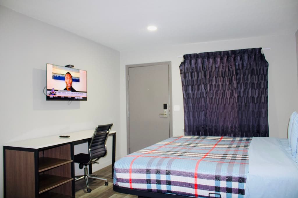 Guest room with entry door, blackout curtains, desk, and TV
