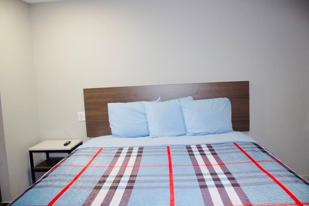 Queen bed with light blue pillows and plaid bedspread