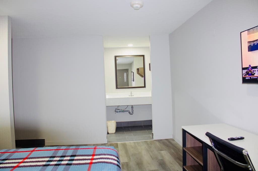 Suite with vanity alcove, desk, and wall-mounted TV
